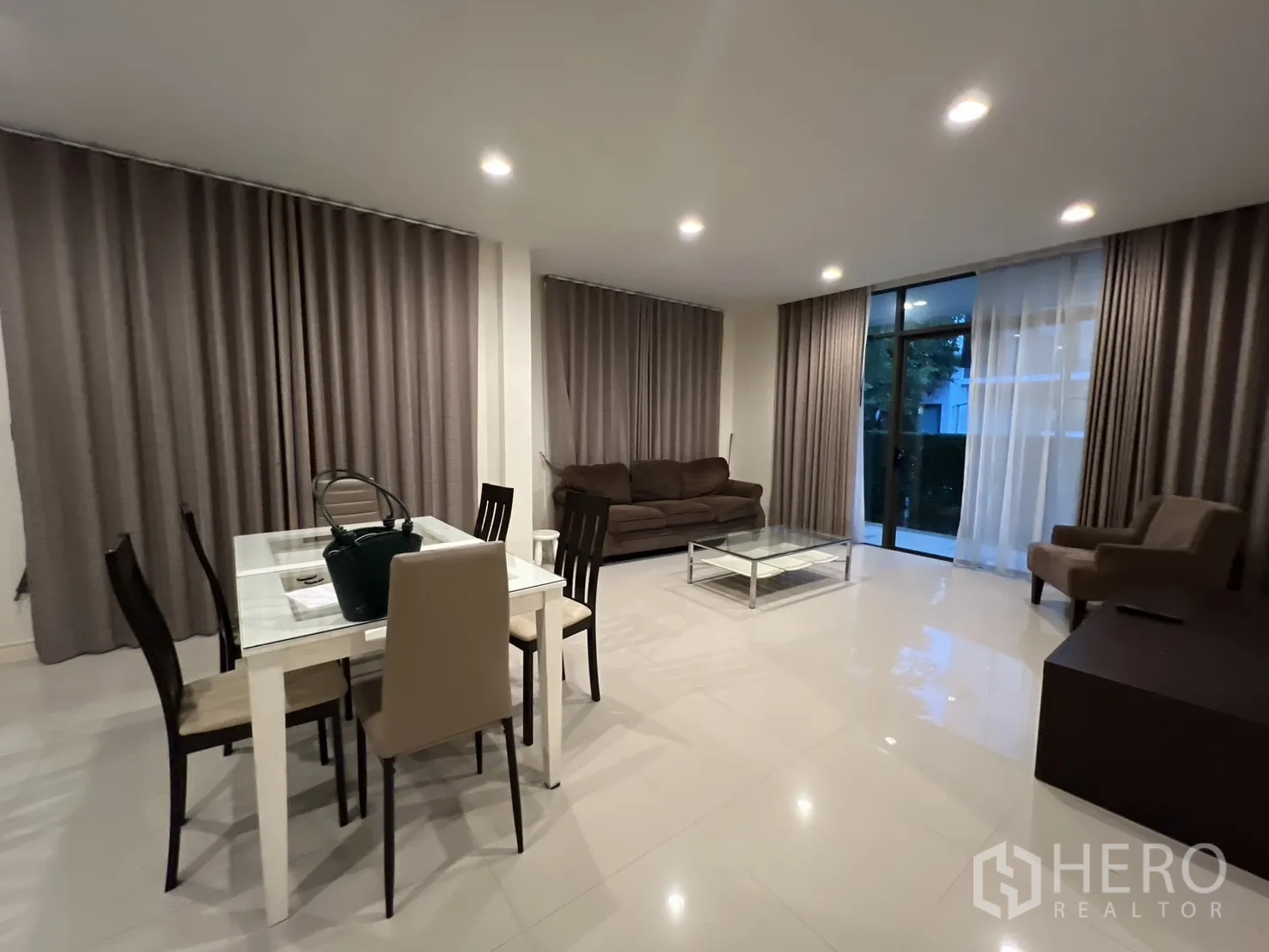Detached House for rent or sale in Bang Kapi, Bangkok - Open-plan living and dining room with large windows and full curtains.