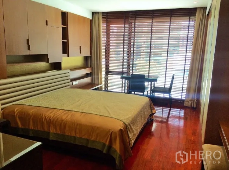 Condominium for rent in Pathum Wan, Bangkok - Spacious master bedroom with large windows, built-in cabinetry and a study desk.