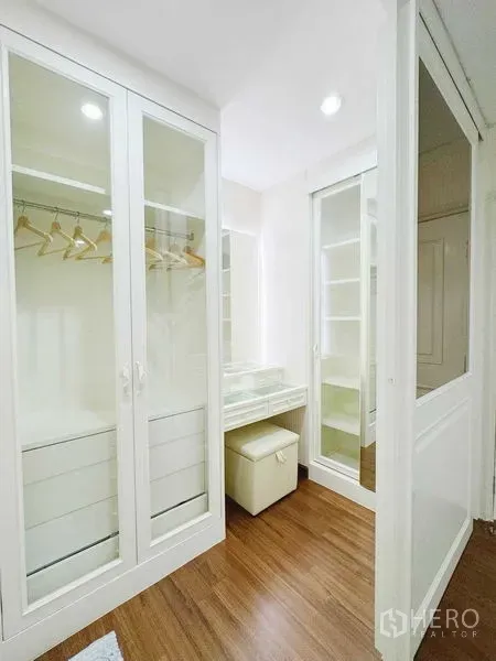 Townhouse for rent in Phra Khanong, Bangkok - Walk-in closet with glass-door wardrobes and a makeup vanity.