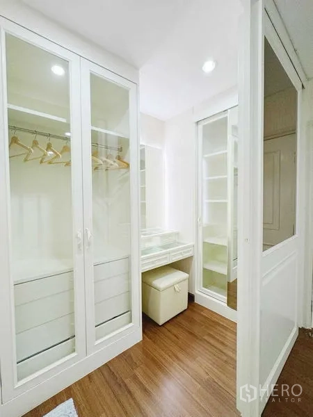 Townhouse for rent in Phra Khanong, Bangkok - Walk-in closet with glass-door wardrobes and a makeup vanity.