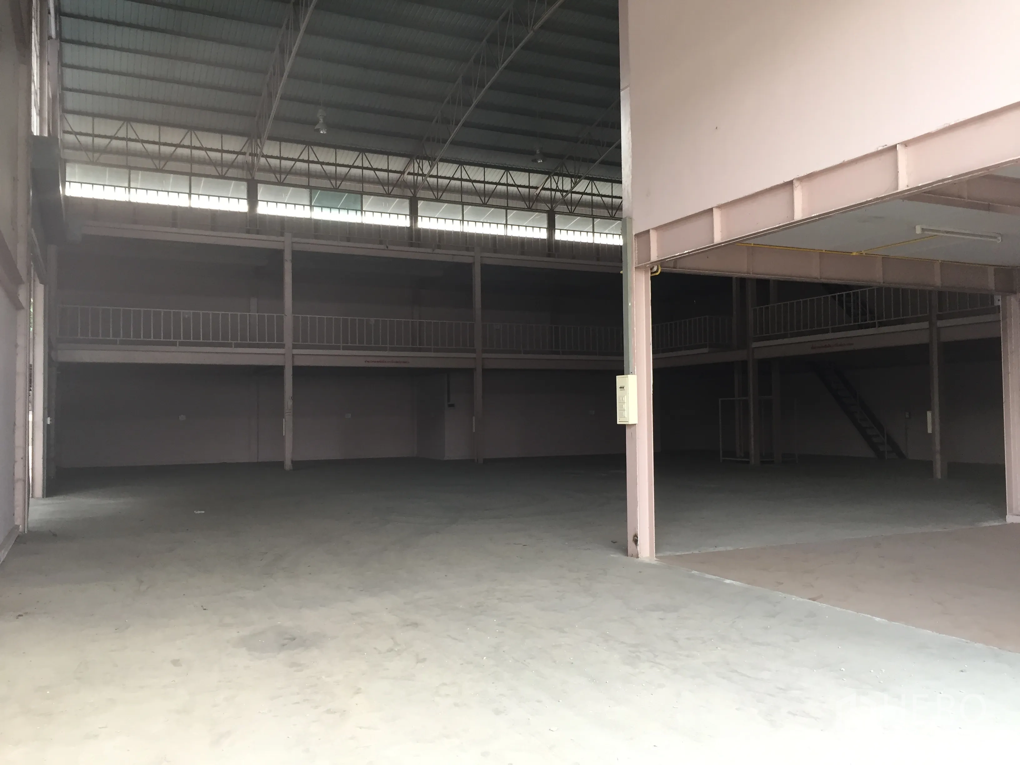 Factory for rent in Lam Luk Ka, Pathum Thani - Open factory floor with steel truss roof and wraparound mezzanine walkways.