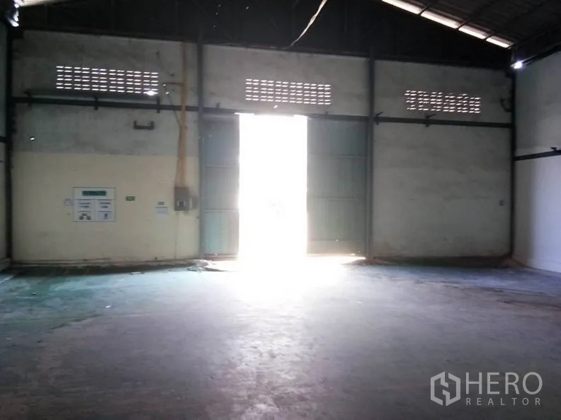 Warehouse for rent in Bang Sao Thong, Samut Prakan - Large metal double doors letting daylight into the warehouse entry area.