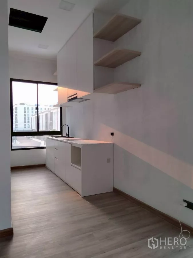 Townhouse for rent in Chatuchak, Bangkok - Secondary pantry kitchen under installation with large window and wood floors.
