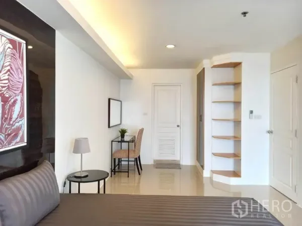 Condominium for rent in Khlong Toei, Bangkok - Bright master bedroom with work desk, built-in corner shelves and glossy tile floors.