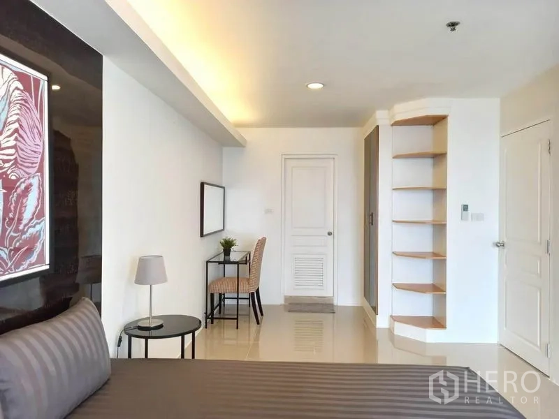 Condominium for rent in Khlong Toei, Bangkok - Bright master bedroom with work desk, built-in corner shelves and glossy tile floors.