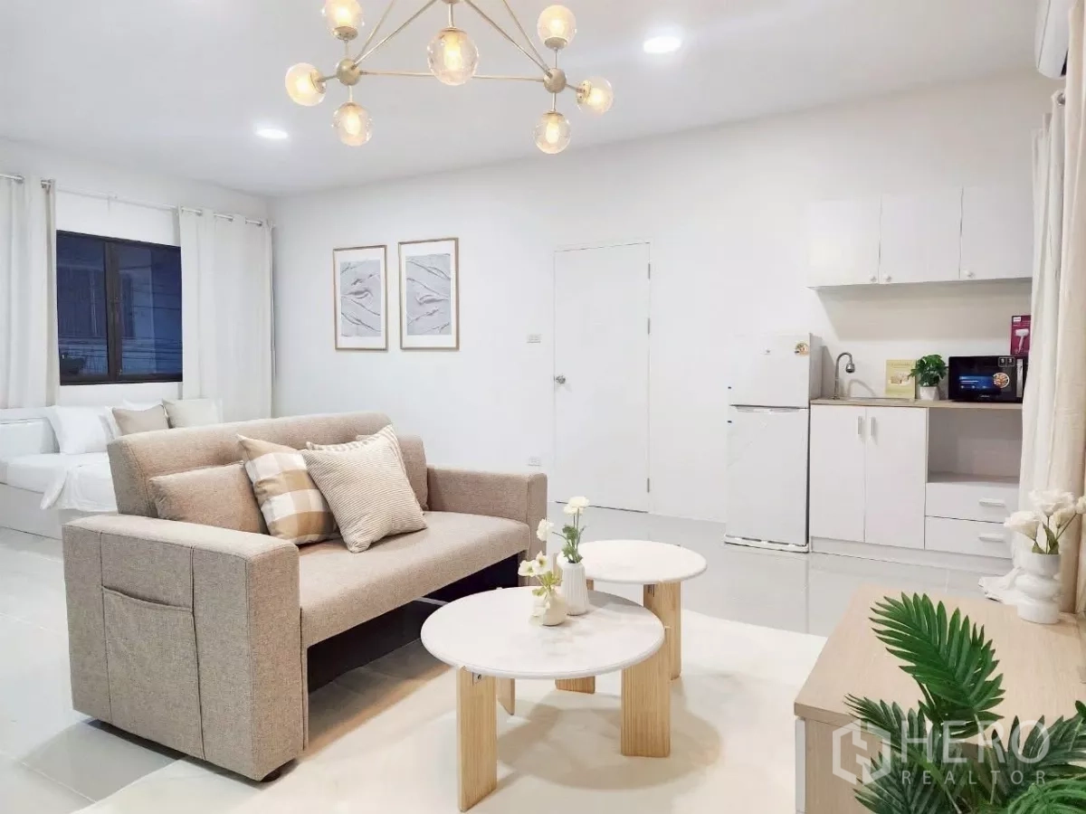 独立式住宅 出租在Chatuchak, Bangkok - 开放式一体空间，沙发、茶几、小厨房与床，白色基调。