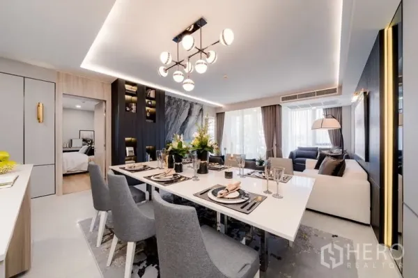 Condominium for sale in Watthana, Bangkok - Alternate view of dining and living area with marble feature wall, built-in shelving and large windows.