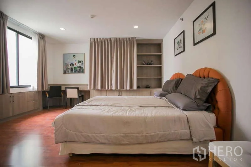 Condominium for rent or sale in Watthana, Bangkok - Second bedroom with large window, built-in shelves and upholstered headboard.