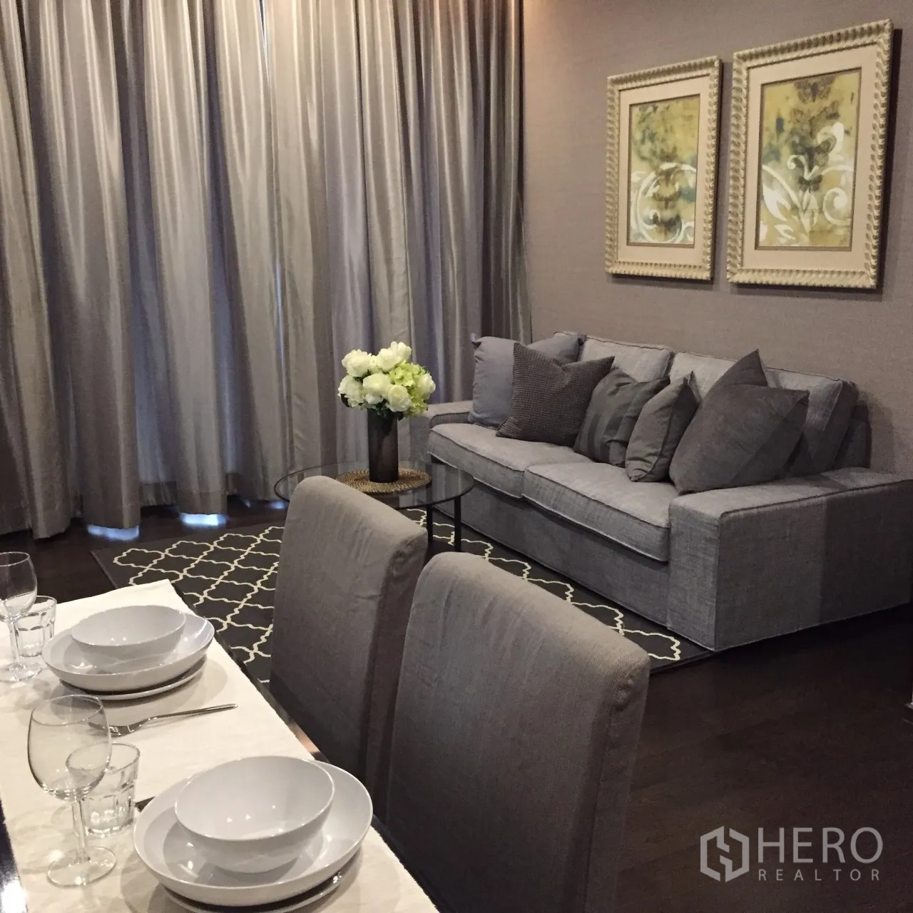 Condominium for rent in Watthana, Bangkok - Dining corner facing long drapes beside a cozy sofa and patterned rug in a Phrom Phong condo.