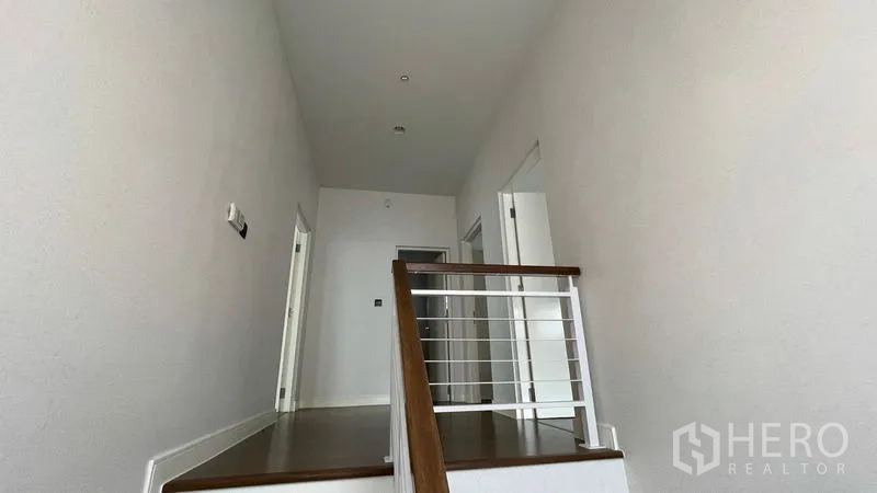 Detached House for rent in Bang Kapi, Bangkok - Upper landing with wooden steps, white railing and doors to bedrooms.