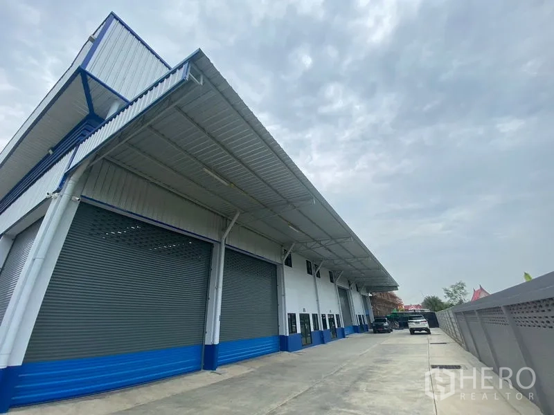 Warehouse for rent in Pathum Thani - Side facade of the warehouse with a long canopy and ample truck turning space.
