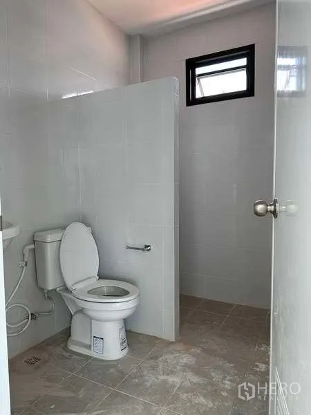 Factory for rent or sale in Bang Bo, Samut Prakan - Clean tiled restroom with toilet and small window in the industrial building.