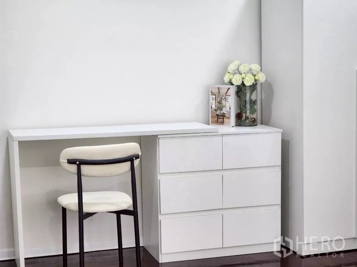 Townhouse for rent in Huai Khwang, Bangkok - Minimal study corner with long desk, white drawers and flower decor.