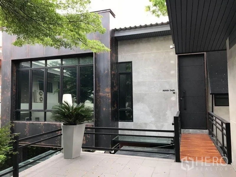 办公空间 出租在Bang Kapi, Bangkok - 外部走道通往行政楼入口，大窗与植物盆栽。
