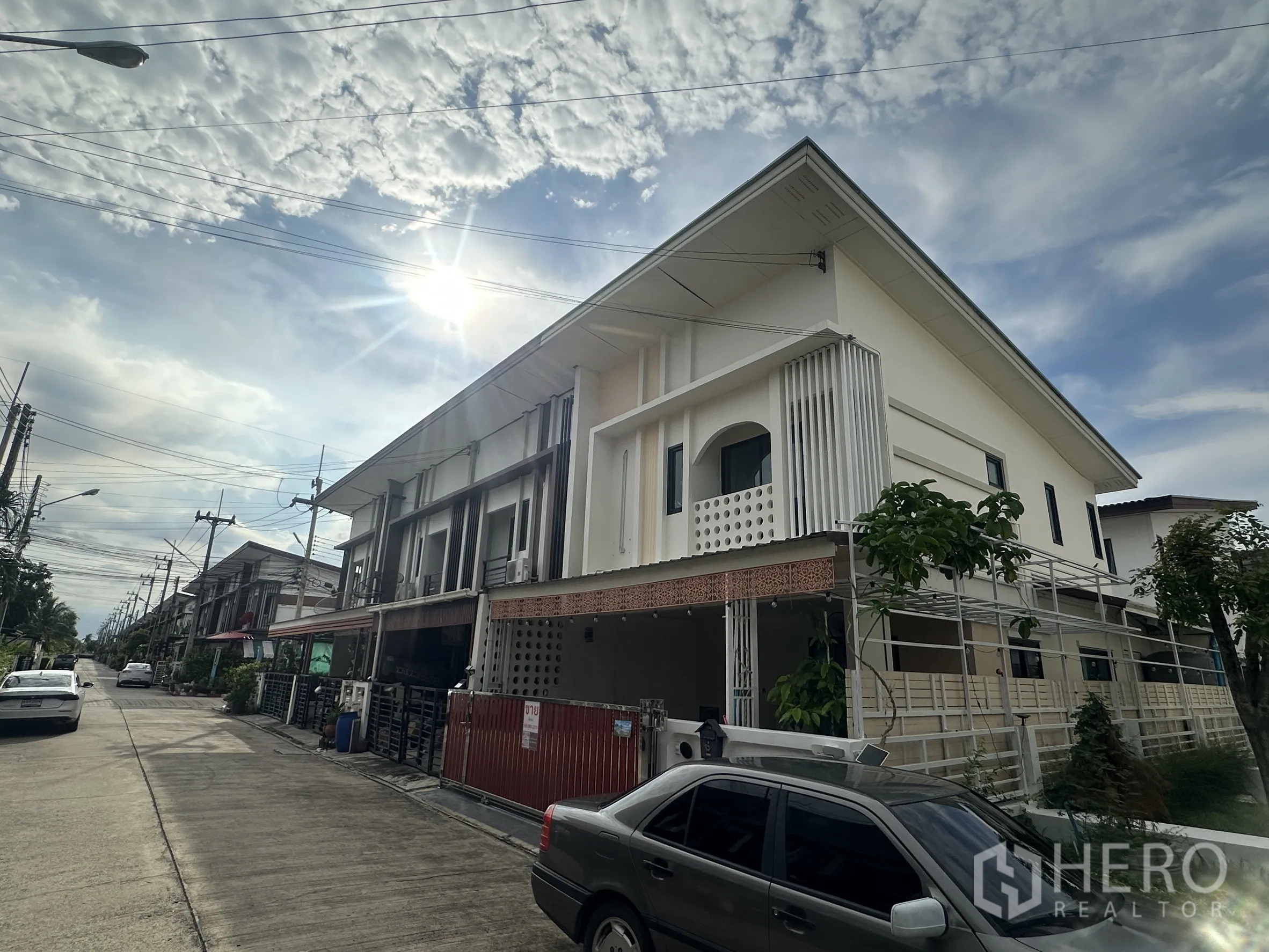 Townhouse for sale in Lam Luk Ka, Pathum Thani - Street view of a modern two-storey townhouse row under a bright sky.