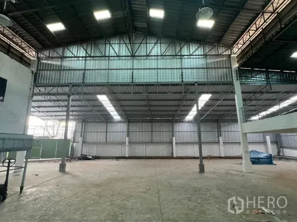 Warehouse for rent in Samut Prakan - High-bay section with steel trusses, skylights and a large entry gate inside the warehouse.