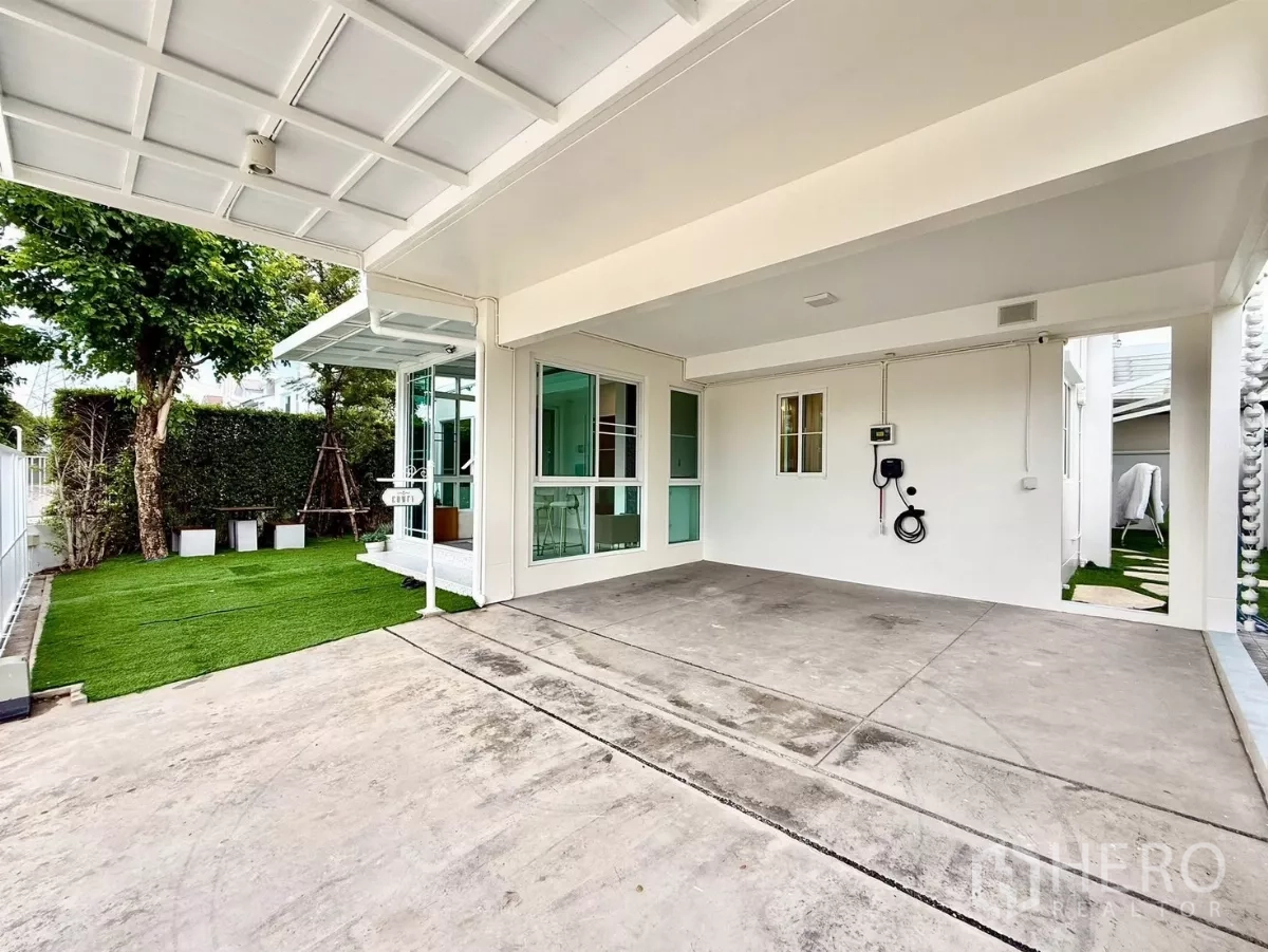 บ้าน ให้เช่าในBang Phli, Samut Prakan - โรงจอดรถในร่มพร้อมที่ชาร์จรถยนต์ไฟฟ้า ข้างสนามหญ้าและประตูกระจก