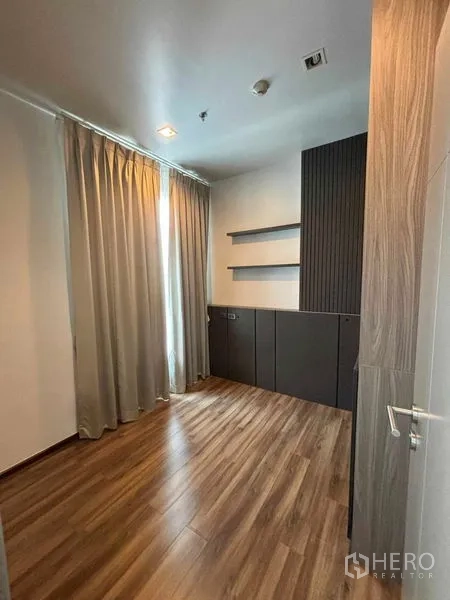 Condominium for rent or sale in Watthana, Bangkok - Spare room or study with wood floors, cabinets and tall curtains.