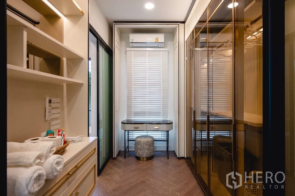 Detached House for rent or sale in Khlong Toei, Bangkok - Walk-in closet with glass wardrobes, shelving and a vanity with stool.