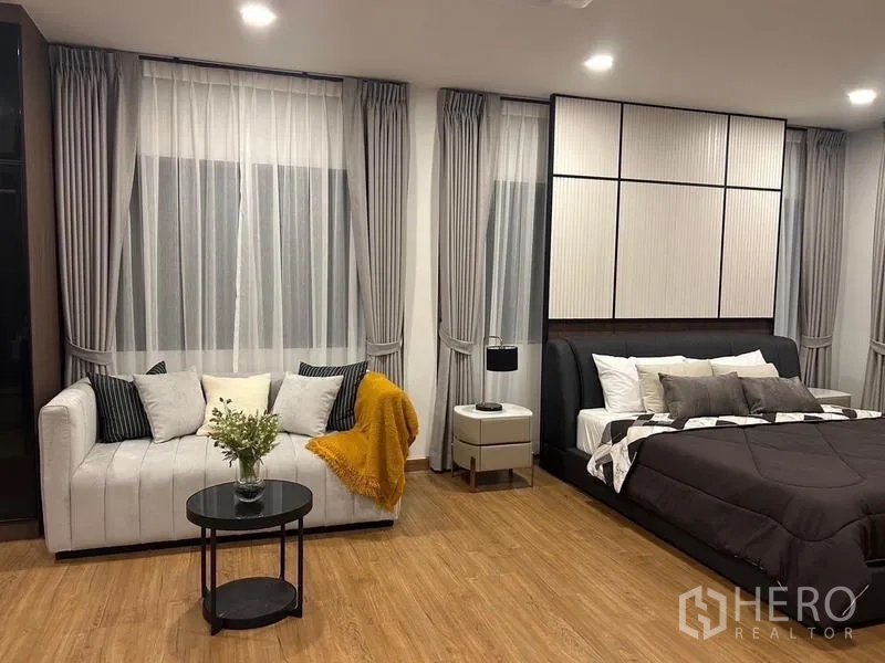 Detached House for rent or sale in Bang Phli, Samut Prakan - Master bedroom corner with tufted sofa, side table and layered curtains.