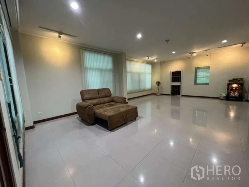 带办公室的家 出租或出售在Min Buri, Bangkok - 宽敞多功能客厅，嵌灯照明、地砖地面与沙发。