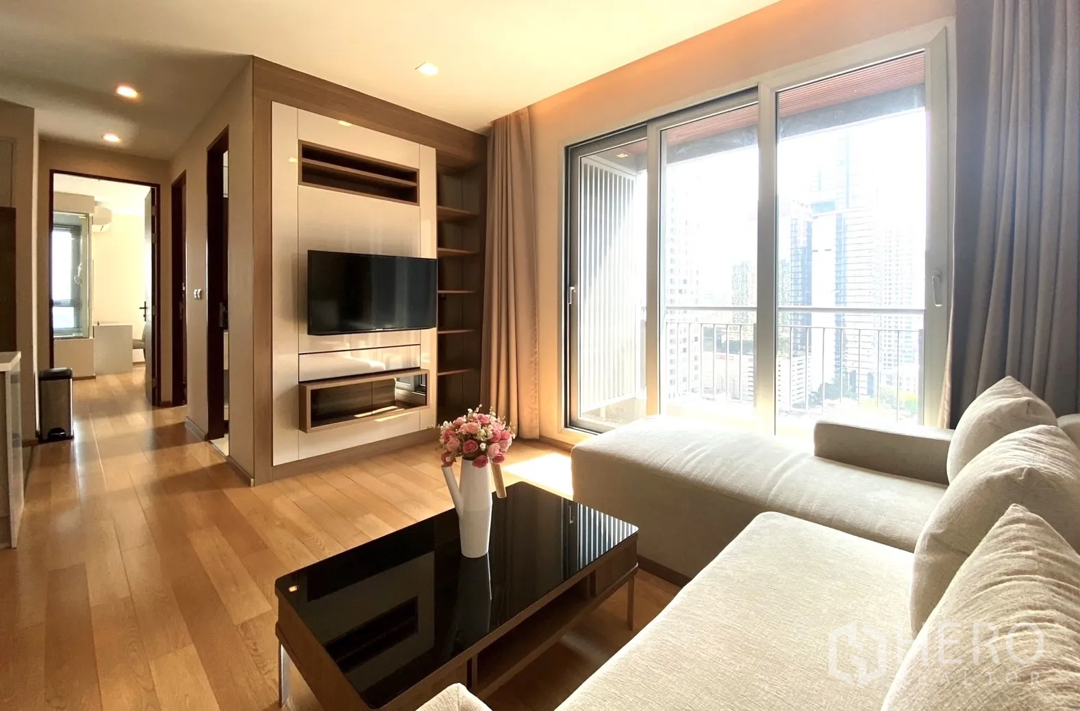 คอนโด ให้เช่าในRatchathewi, Bangkok - ห้องนั่งเล่นรับแสงพร้อมโซฟาเข้ามุม ประตูระเบียง และวิวสกายไลน์กรุงเทพฯ