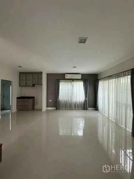 Detached House for rent in Samut Prakan - Large living-dining room with full-height curtains and garden views.