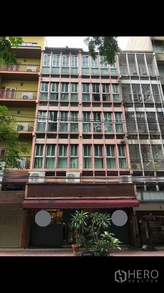 อาคารพาณิชย์ ให้เช่าในBang Rak, Bangkok - อาคารพาณิชย์หลายชั้นด้านหน้า กระจกบานใหญ่ กันสาด และกระถางต้นไม้บนถนนสีลม