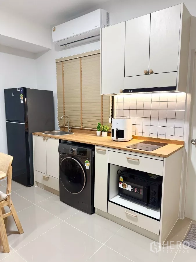 Townhouse for rent in Bang Phli, Samut Prakan - Close-up of built-in kitchen with electric hob, hood, microwave, sink and storage.