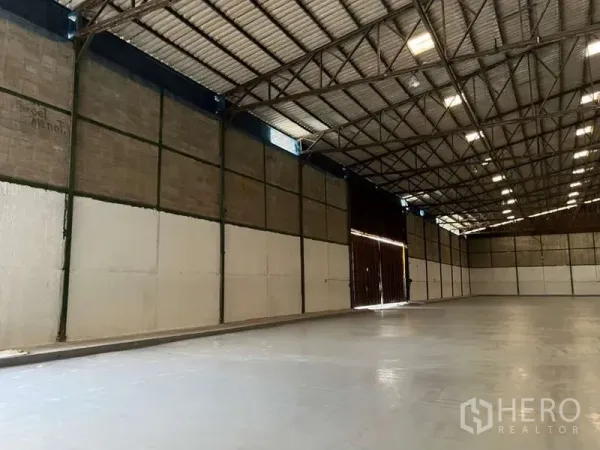Factory for rent in Bang Pakong, Chachoengsao - Side bay of the warehouse showing large sliding doors, insulated wall panels, and smooth concrete flooring.