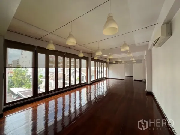 办公空间 出租在Watthana, Bangkok - 开放式办公室，实木亮面地板、吊灯与整面落地窗，采光充足并可观景。