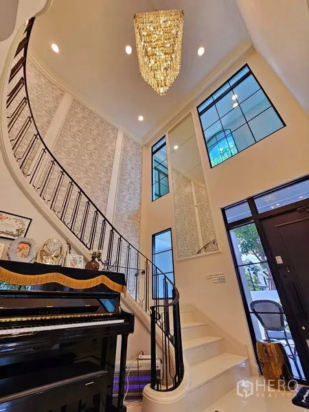 Detached House for rent or sale in Saphan Sung, Bangkok - Curved staircase and sparkling chandelier viewed from the entry hall.