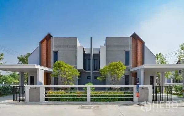 Detached House for sale in Lam Luk Ka, Pathum Thani - Front elevation of a modern loft-style detached house with brick accents, garden and fence.