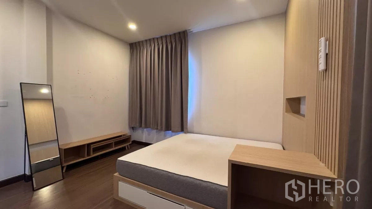 Detached House for rent or sale in Saphan Sung, Bangkok - Cozy bedroom with platform bed, warm wood headboard wall and thick gray curtains.
