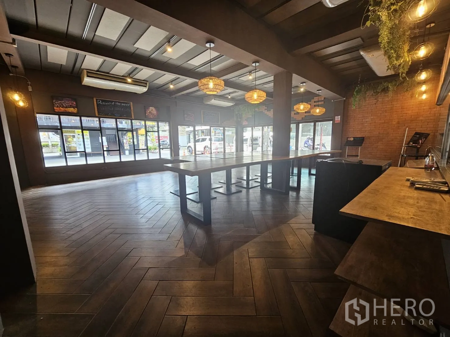 Retail Space for rent in Watthana, Bangkok - Large customer area with floor-to-ceiling windows, central communal table and warm pendant lighting.