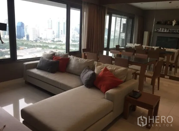 公寓 出租或出售在Sathon, Bangkok - 开放式客餐厅配转角沙发与全景落地窗，尽享城市与公园景观，位于曼谷沙吞公寓。