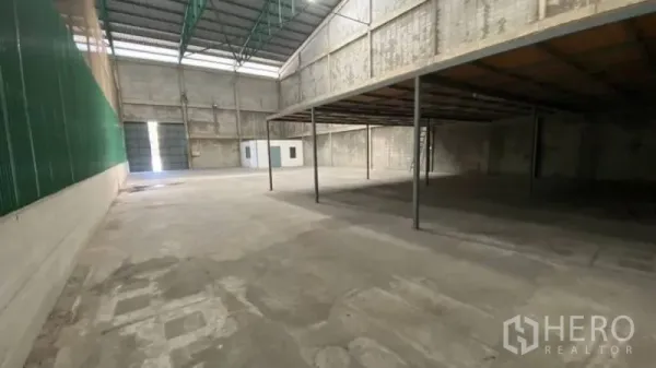 Warehouse for rent in Prawet, Bangkok - Spacious warehouse interior with high ceiling, skylights, concrete floor, and a steel mezzanine for added storage.