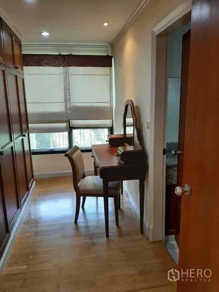 Apartment for rent in Watthana, Bangkok - Walk-in dressing nook featuring built-in wardrobes, a vanity desk, and a door to the bathroom.