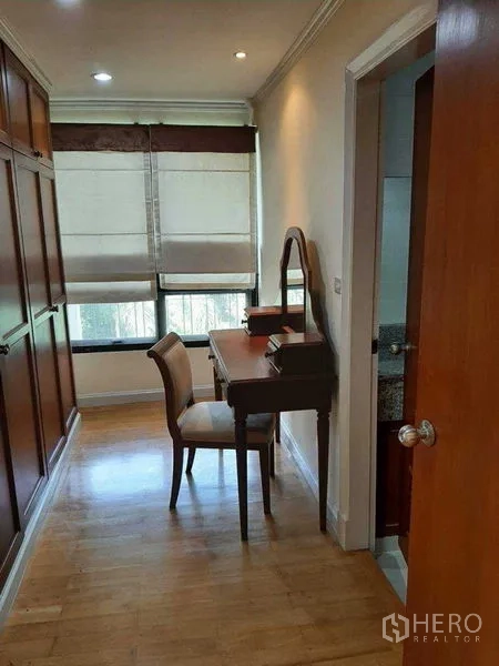 Apartment for rent in Watthana, Bangkok - Walk-in dressing nook featuring built-in wardrobes, a vanity desk, and a door to the bathroom.