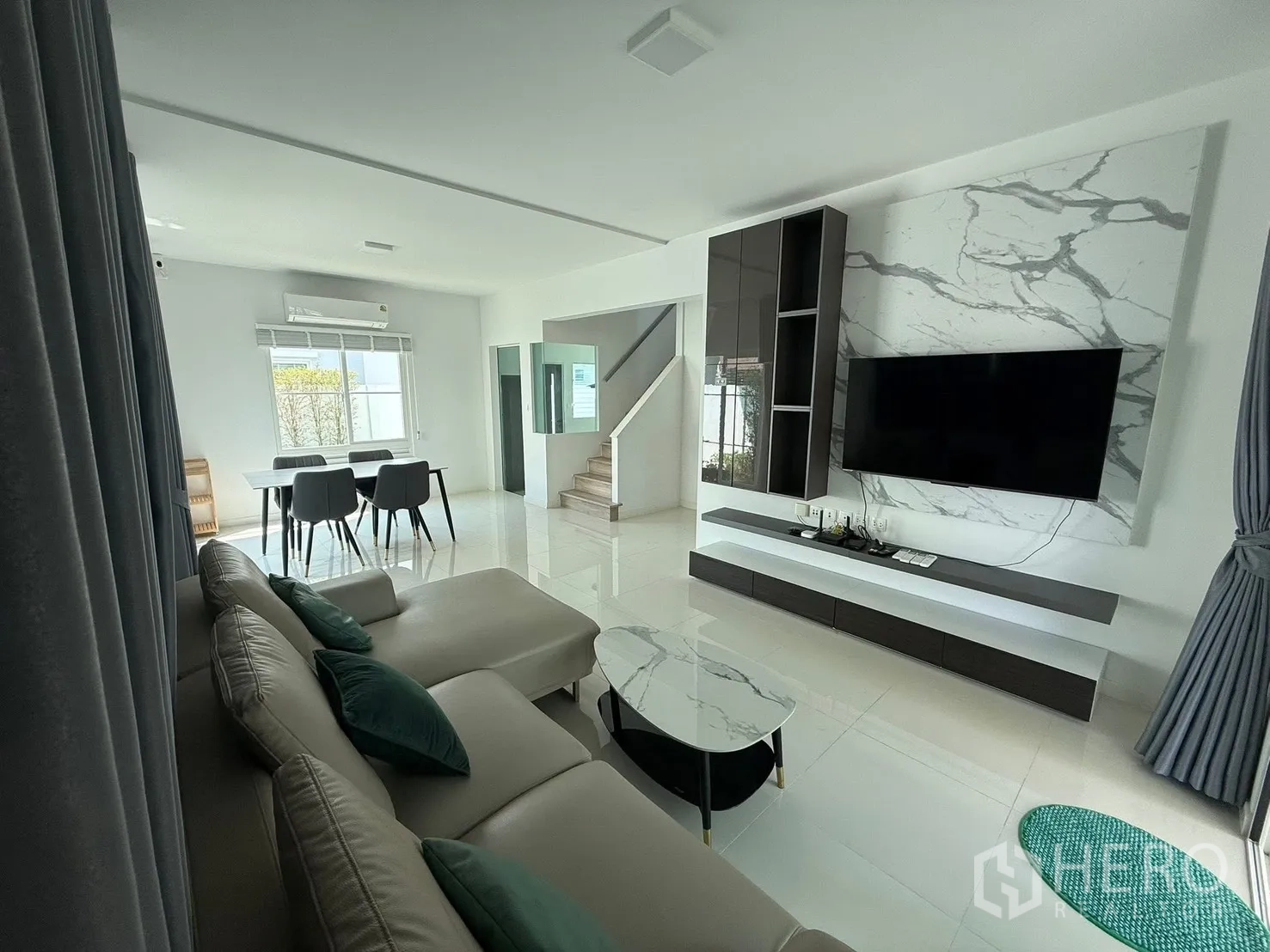 独栋房屋 for rent in Bang Phli, Samut Prakan - 客餐厅一体空间，转角沙发、大理石纹电视墙与餐桌。
