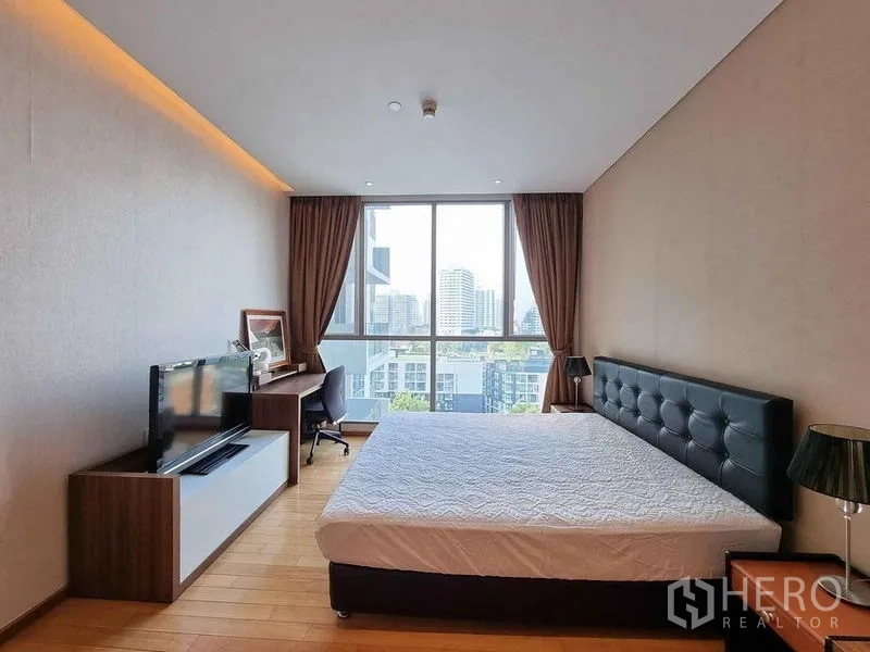公寓 出租在Watthana, Bangkok - 主卧采光充足，落地窗城市景观，配书桌与电视。