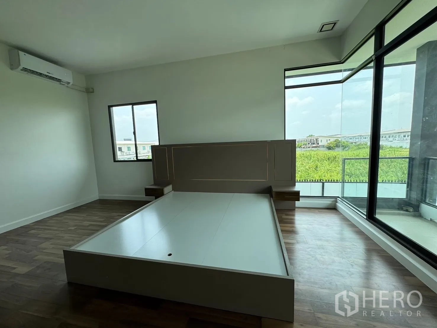 Detached House for rent in Prawet, Bangkok - Primary bedroom with corner floor-to-ceiling windows, balcony and bed base.