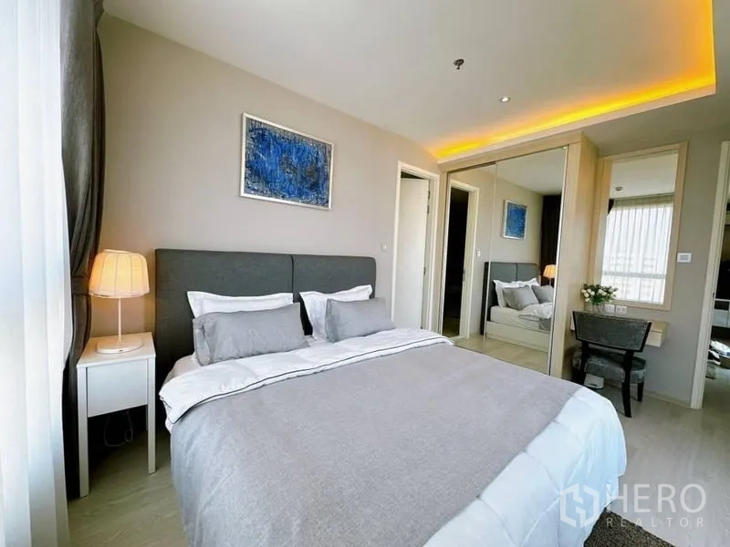 Condominium for rent in Watthana, Bangkok - Cozy bedroom with upholstered bed, mirrored wardrobe and warm ceiling lights.