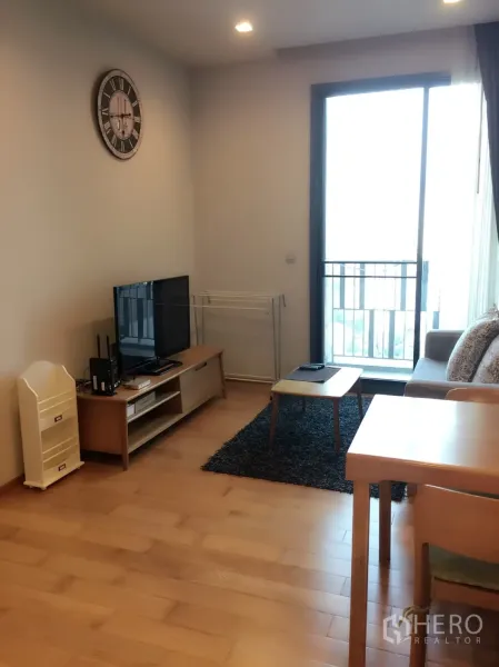 公寓 出租在Khlong Toei, Bangkok - 明亮客厅带木地板、沙发与电视柜，滑动玻璃门连通阳台，靠近BTS通罗的曼谷公寓。