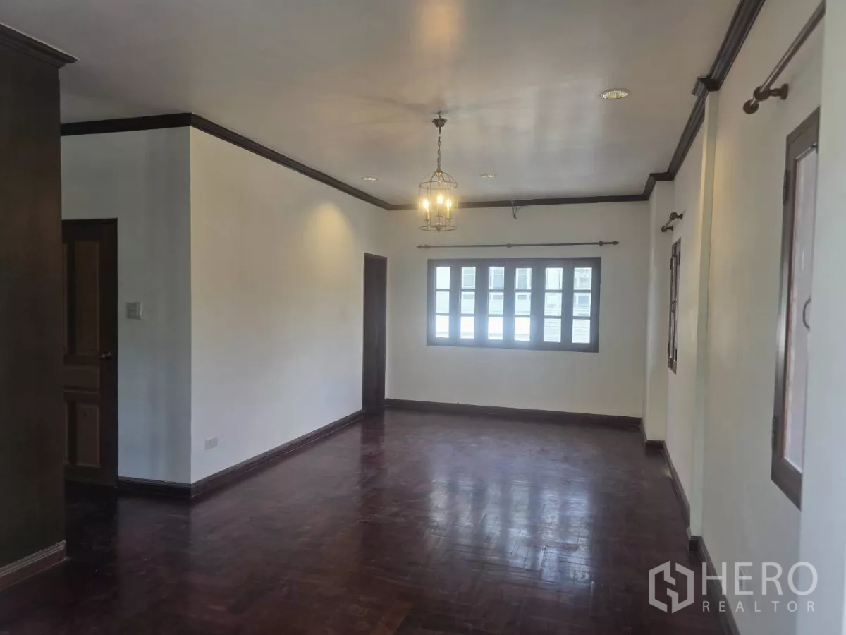 Detached House for rent in Phra Khanong, Bangkok - Spacious master bedroom with dark hardwood floors and wide windows.