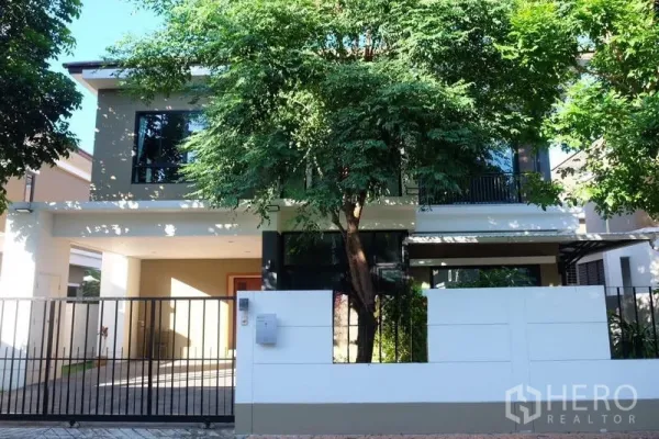 บ้าน ให้เช่าในBang Phli, Samut Prakan - มุมมองหน้าบ้านเดี่ยวสมัยใหม่ พร้อมรั้วและต้นไม้ร่มรื่น
