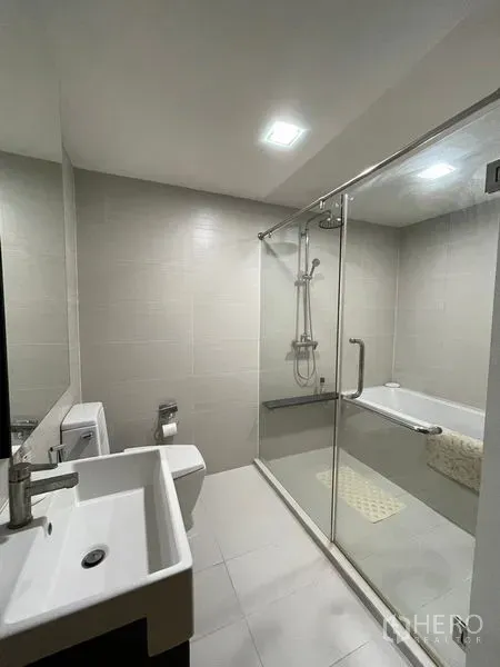 Condominium for sale in Khlong Toei, Bangkok - Bathroom with glass partition, bathtub and overhead shower.