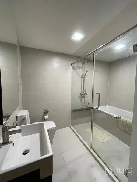 Condominium for sale in Khlong Toei, Bangkok - Bathroom with glass partition, bathtub and overhead shower.