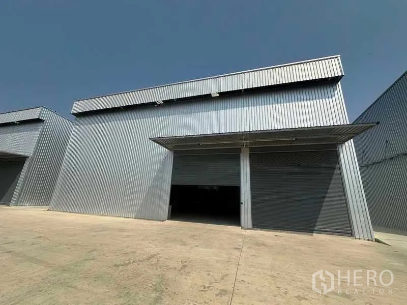 Factory for rent in Wang Noi, Phra Nakhon Si Ayutthaya - Angled exterior view of the steel-clad factory with two roller doors and a broad driveway.