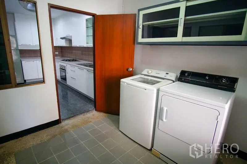Apartment for rent in Watthana, Bangkok - Separate laundry room with washing machine, dryer, and overhead storage cabinets.